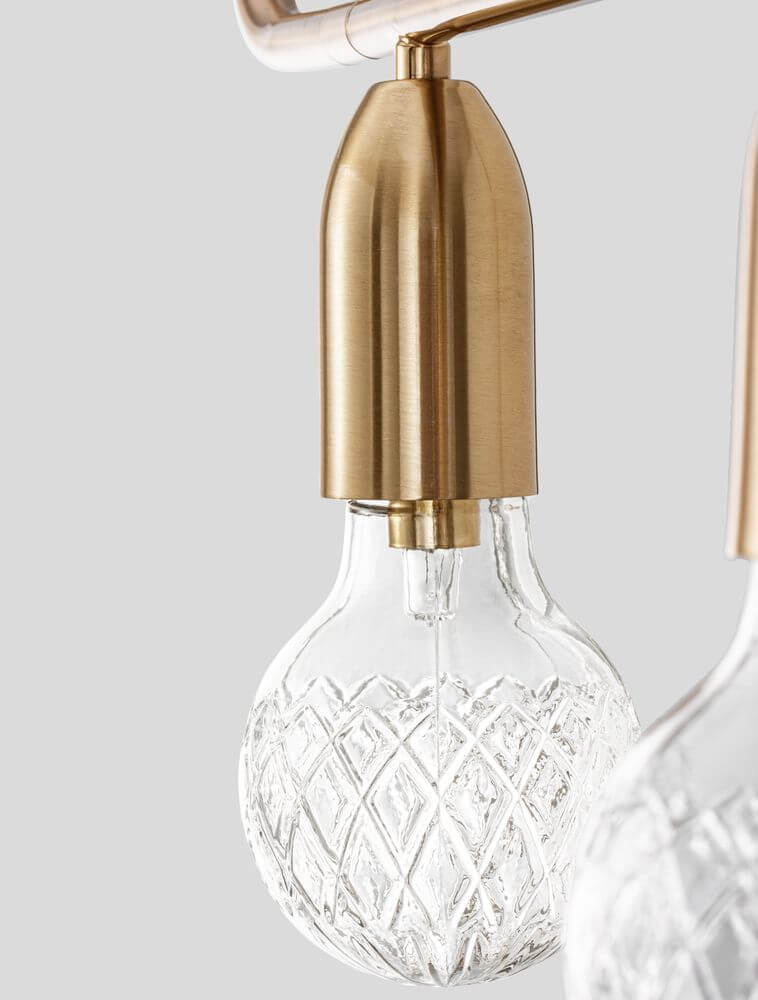 Detailansicht der Veda Pendelleuchte mit goldenem Lampenständer und transparentem, facettiertem Glaskugel-Lampenaufsatz.