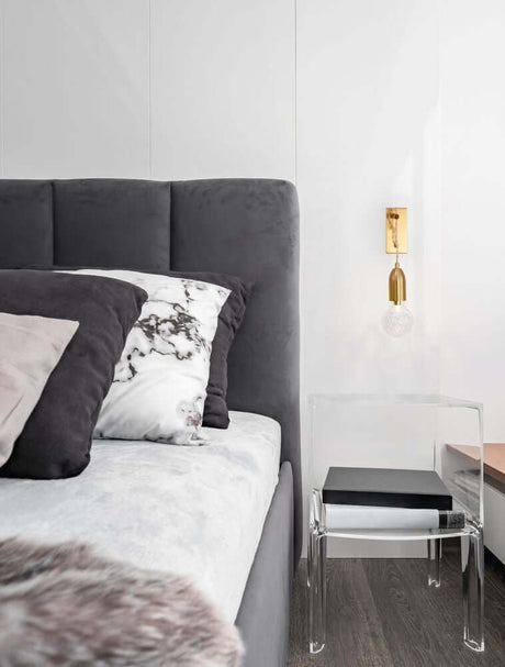 Veda Wandleuchte G9 an moderne Wand über stilvollem Bett und Klarsichtstuhl in elegantem Schlafzimmer.