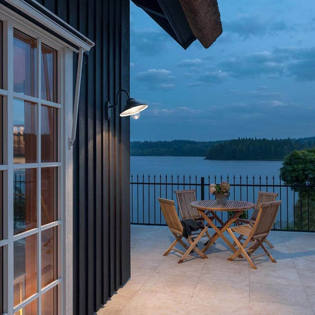 Vega LED outdoor wall light 700lm, 3000K black, clear glass on a modern house wall with terrace and view of the water.