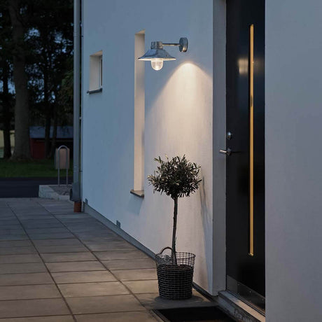 Vega LED Außen-Wandleuchte 3000K an einer Wand mit Beleuchtung und Pflanze im Korb.