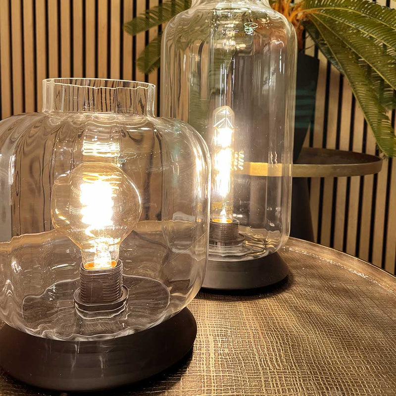moderne Glaskerzenleuchter mit leuchtenden Glühbirnen auf einem eleganten Tisch