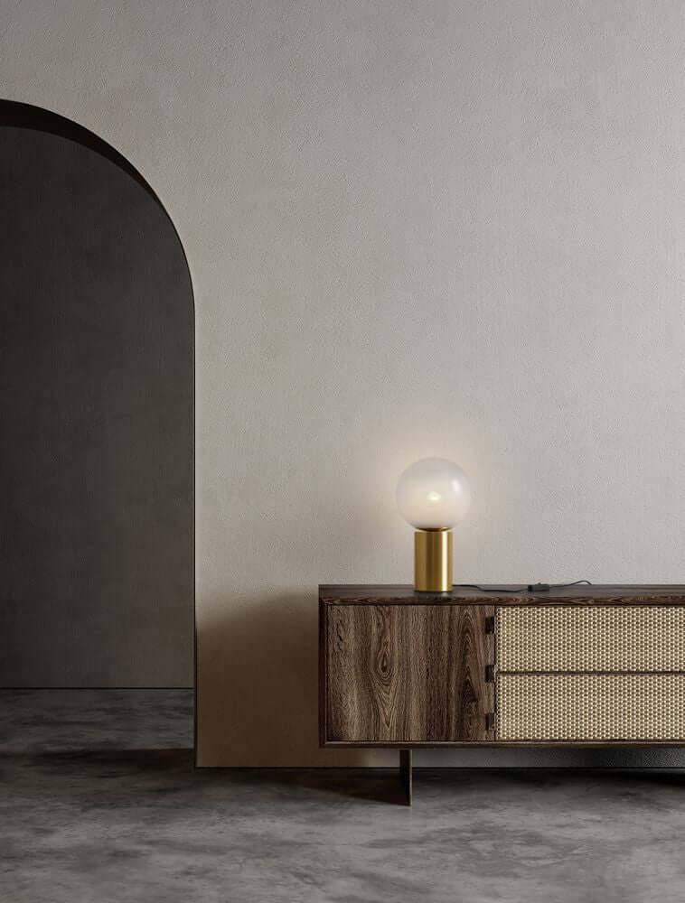 Vita Tischleuchte in Gold und Weiß auf einem Holzschrank, warmes Ambiente für modernes Wohnen.