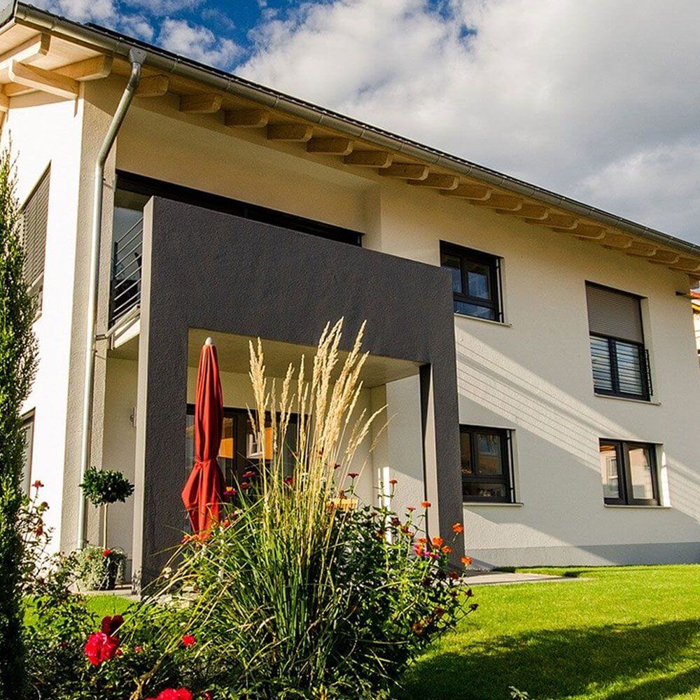 Modernes Einfamilienhaus mit schönem Garten und rotem Sonnenschirm, ideale Planung für Vor-Ort Termin.