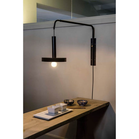 Wand-Hängeleuchte WHIZZ Schwarz, Goldfarben über einem Holztisch mit Geschirr und Dekoration.