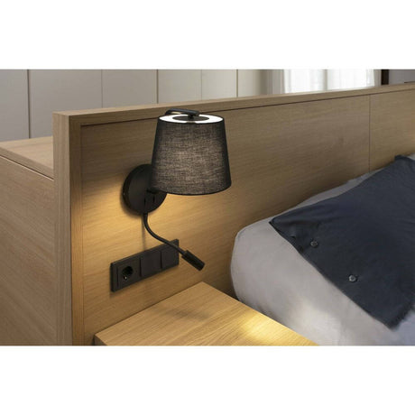Vegglampe BERNI med LED-leselys sort ved en seng på soverommet, stilfullt design og praktisk belysning.