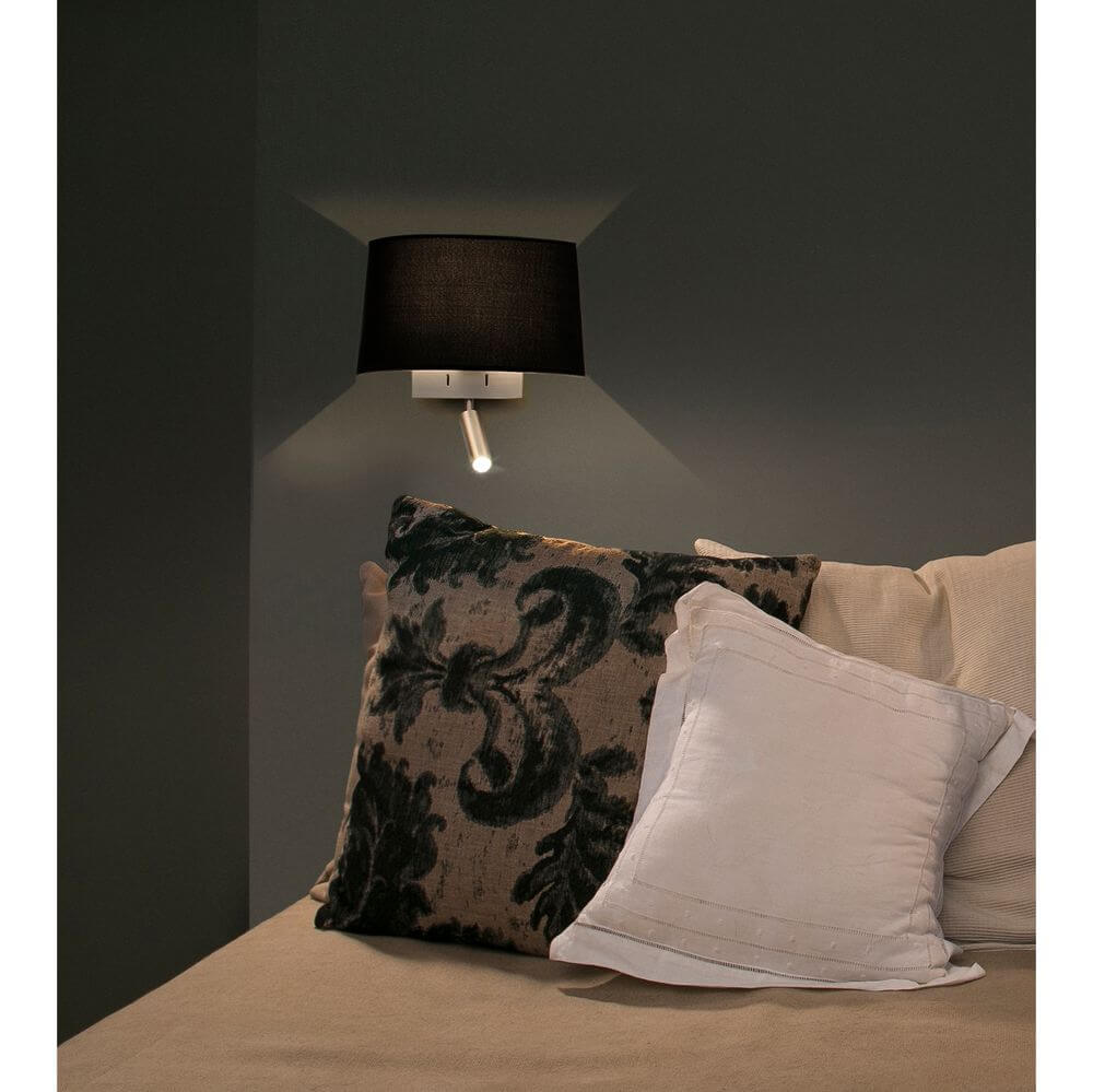 Wandlampe VOLTA mit LED-Leselicht 2700K Nickel, Schwarz neben Kissen auf einem Sofa.