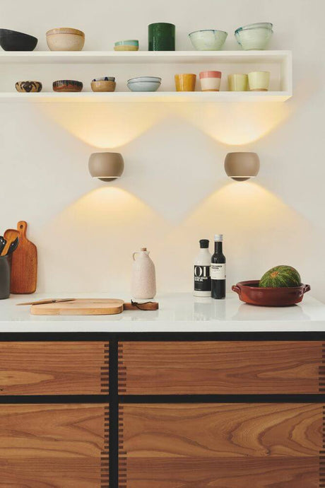 L’applique murale Belir diffuse une lumière élégante au-dessus d’un plan de cuisine moderne et crée une atmosphère chaleureuse.