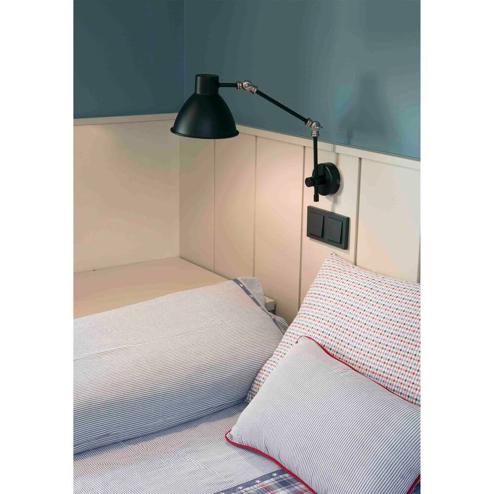 Wandleuchte CELIA Schwarz über dem Bett mit Kissen und modernem Schlafraumdesign.
