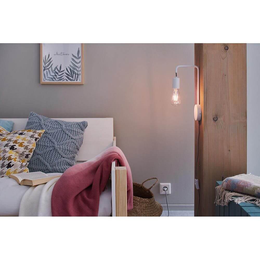 Wandleuchte Calvani Dimmbar Weiß an einer Wand neben einem Bett, ideal als Leselampe mit dekorativem Leuchtmittel.