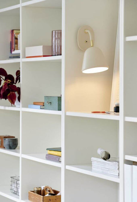 Applique Fleur 15 sur une bibliothèque, design nostalgique avec tête de lampe orientable en beige poudré.