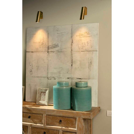 Wandleuchte LINK Bronze über einem Holztisch mit Blauen Vasen und abstrakter Kunst im Hintergrund.