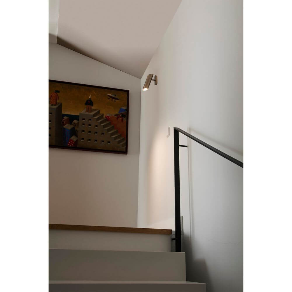 Wandleuchte LINK Bronze an einer Treppe mit Kunstwerk im Hintergrund.