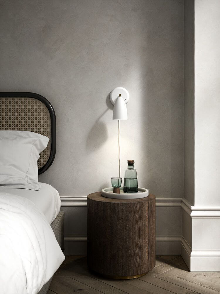 Wandleuchte Nexus 2 über einem Nachttisch mit Glasflasche und Gläsern, modernes nordisches Design.