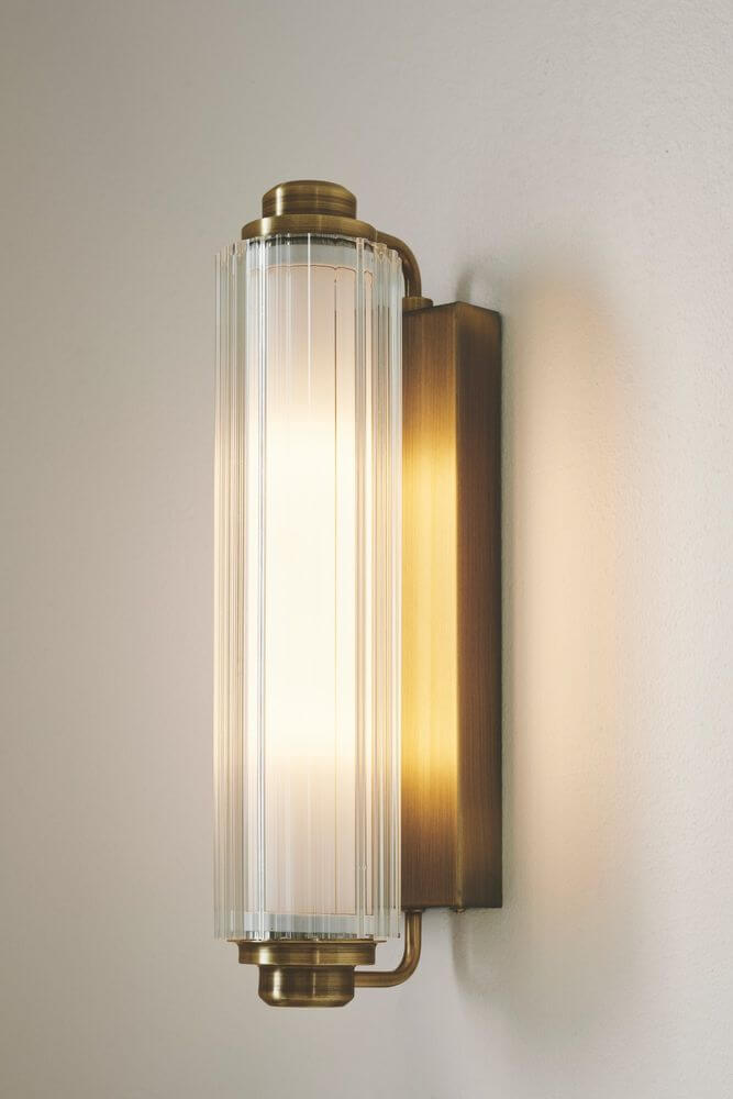 Wandleuchte Nimal Double IP44 mit elegantem Design aus klarem Glas und goldfarbener Halterung, ideal für modernes Ambiente.