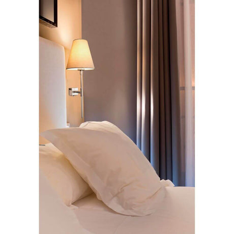 Wandleuchte SABANA Nickel-Matt, Beige neben einem Bett mit weißen Kissen und Vorhängen.