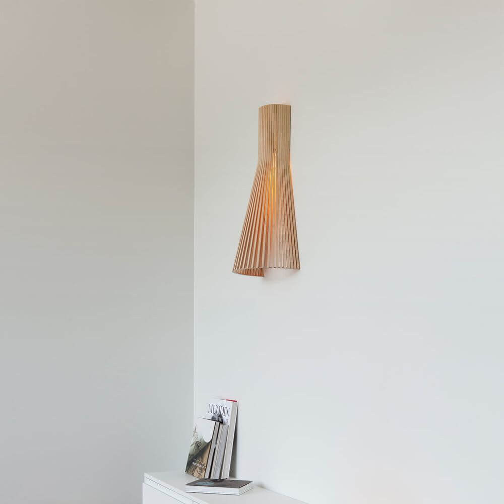 Wandleuchte Secto Small 4231 aus Holz 45cm an einer Wand mit Bücherstapel im Hintergrund