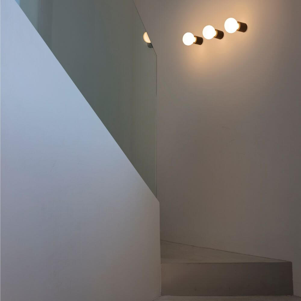 Moderne Wandleuchte TEN Kupfer mit drei Lichtquellen in einem eleganten Treppenhaus.