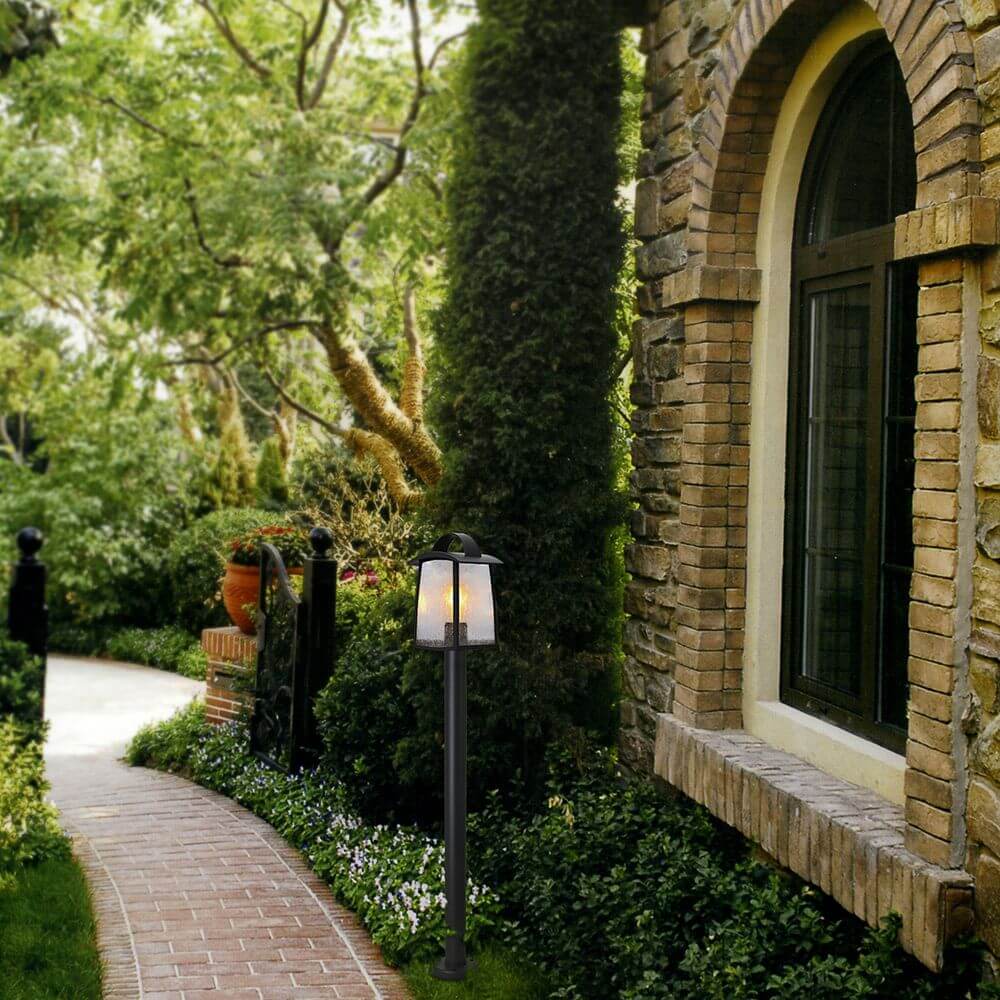 Wegeleuchte Kelsey IP44 103cm Schwarz beleuchtet einen Gartenweg neben einem Steinhaus.