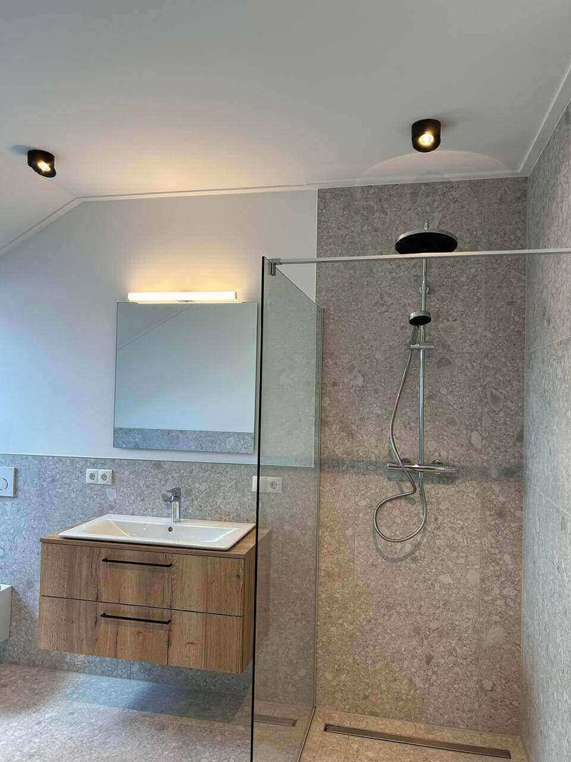 Modernes Badezimmer mit Dusche, Holzwaschtisch und Spiegel, elegant und hell gestaltet.