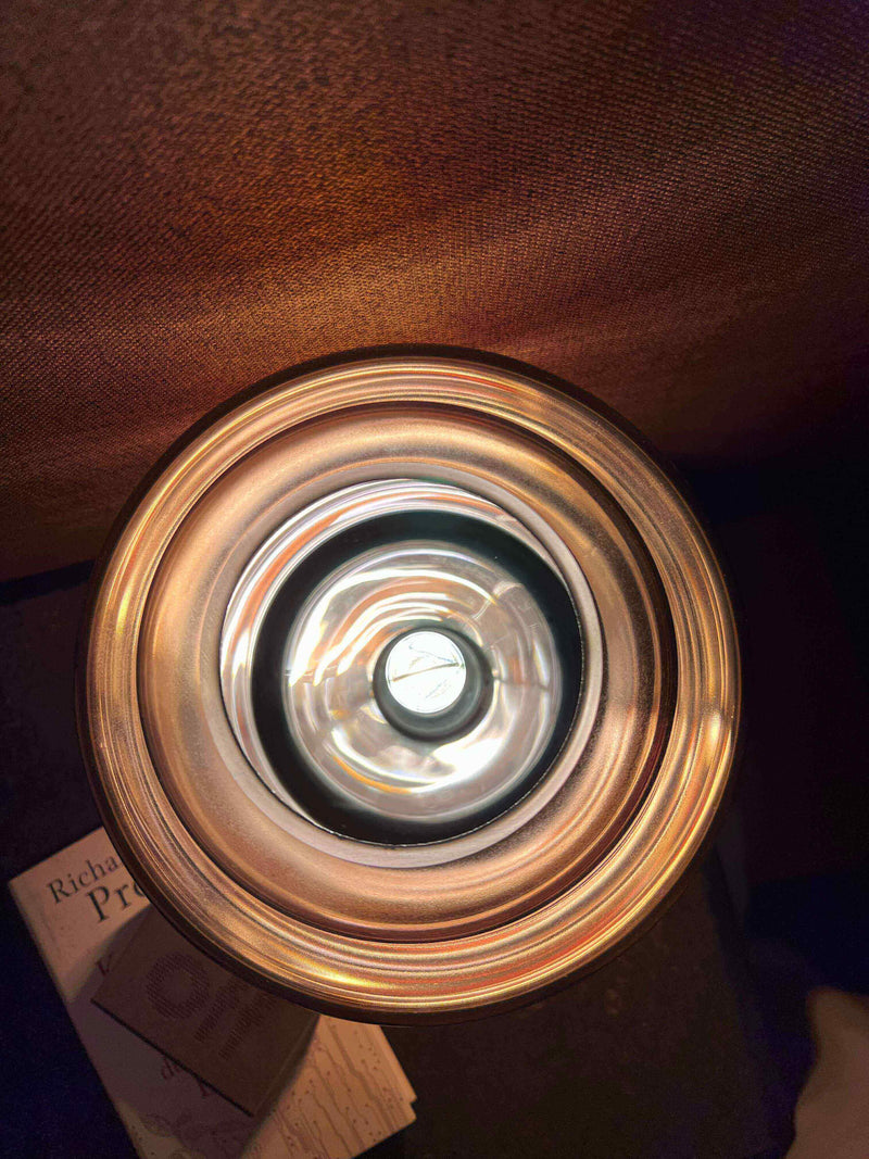 Eine oberhalb gezeigte Lampe mit reflektierendem Licht und einem Buch im Hintergrund.