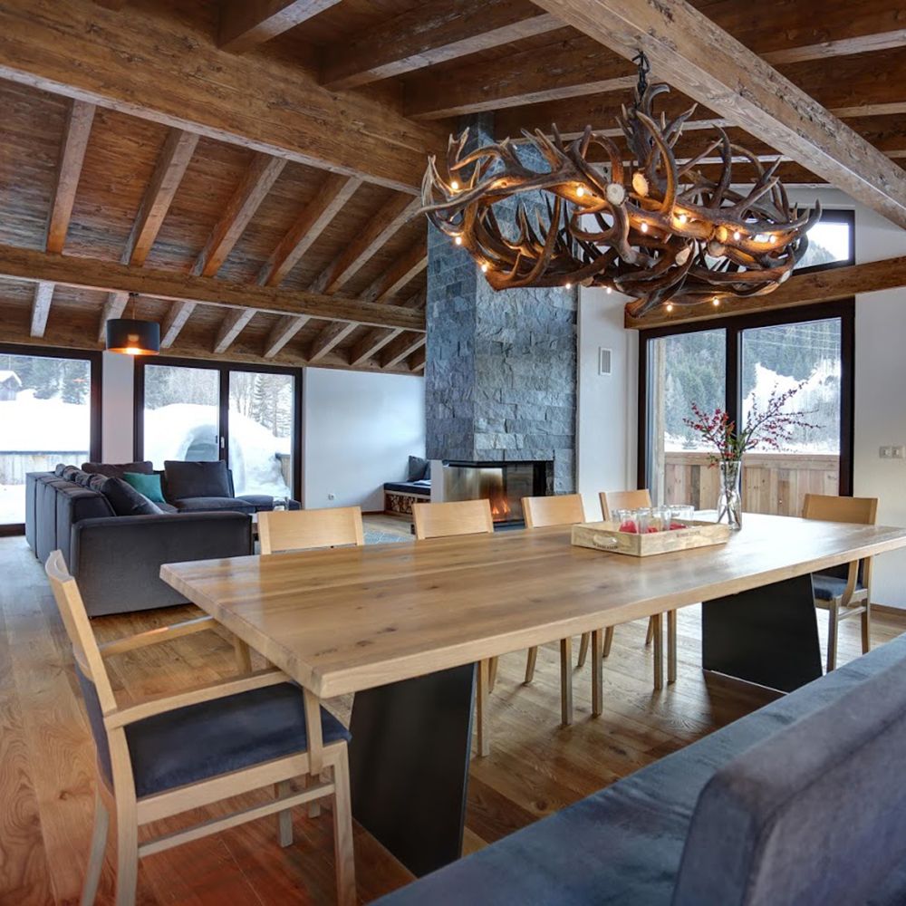 XXL Rothirsch LED Geweihlampe im Chalet mit rustikaler Holzdecke und modernem Esstisch.