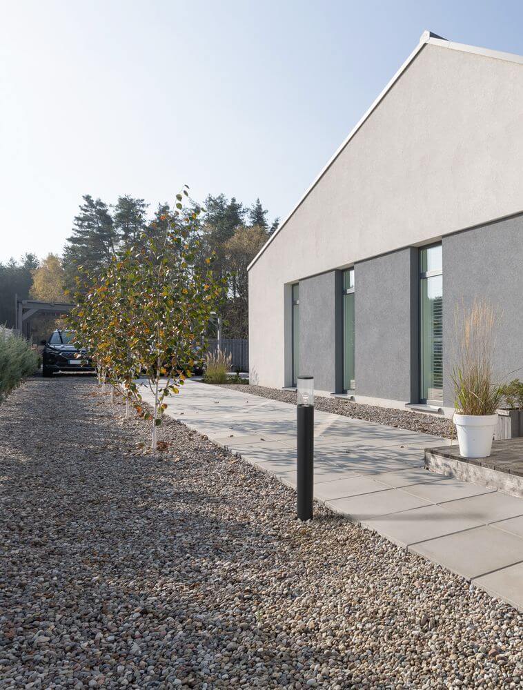 Zosia Außenwegeleuchte Dunkelgrau IP65 beleuchtet modernen Gartenweg neben einem modernen Haus.