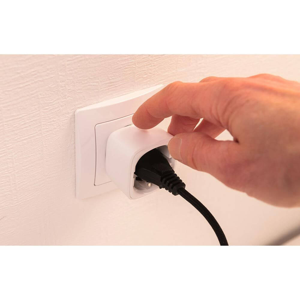 Hand, die einen Zwischenstecker Smart Home Zigbee in die Steckdose einführt.