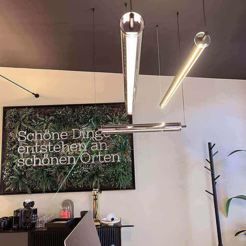 Moderne Leuchten über einem eleganten Interieur mit Pflanzenwand und inspirierendem Spruch.