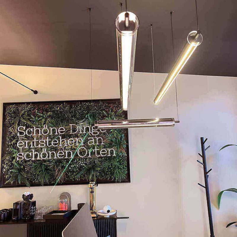 Moderne Leuchten über einem eleganten Interieur mit Pflanzenwand und inspirierendem Spruch.