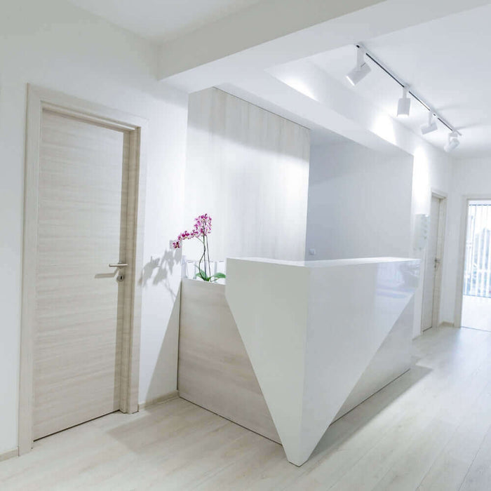 Moderne Empfangstheke in einer hellen und minimalistischen Praxis mit Blumen. Lichtdurchfluteter Raum.