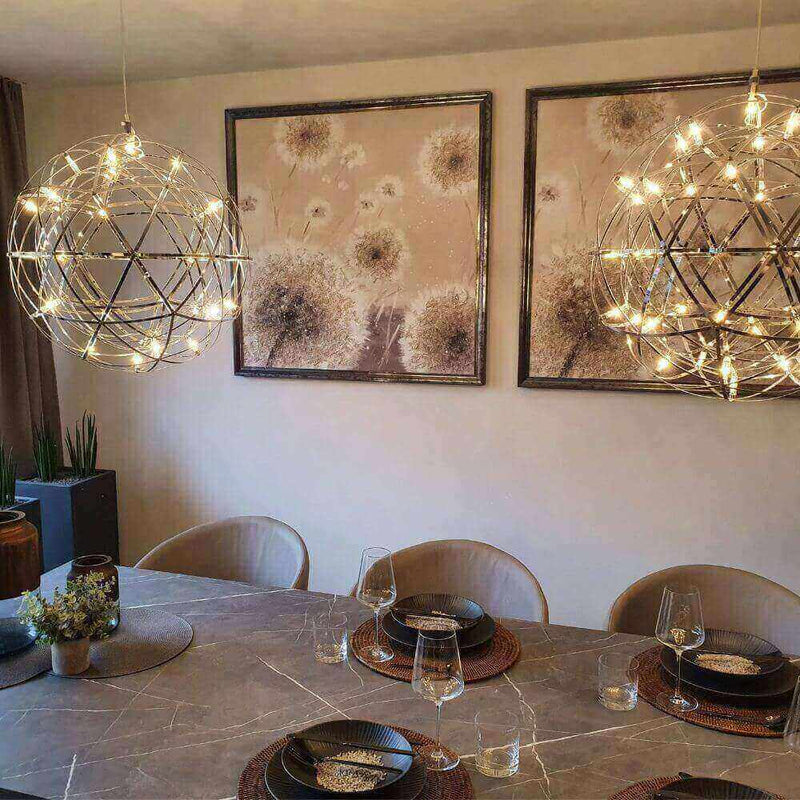 Moderne Esszimmerbeleuchtung mit zwei hängenden Lampen und dekorativen Bildern an der Wand.