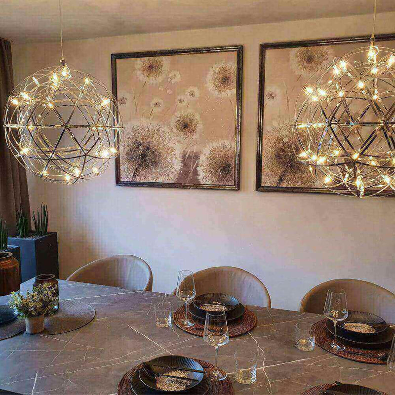 Moderne Esszimmerbeleuchtung mit zwei hängenden Lampen und dekorativen Bildern an der Wand.