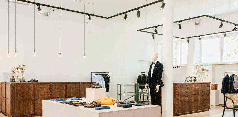 Eleganter Modegeschäftsinterieur mit minimalistischer Dekoration, stilvolle Kleidung und moderner Beleuchtung.