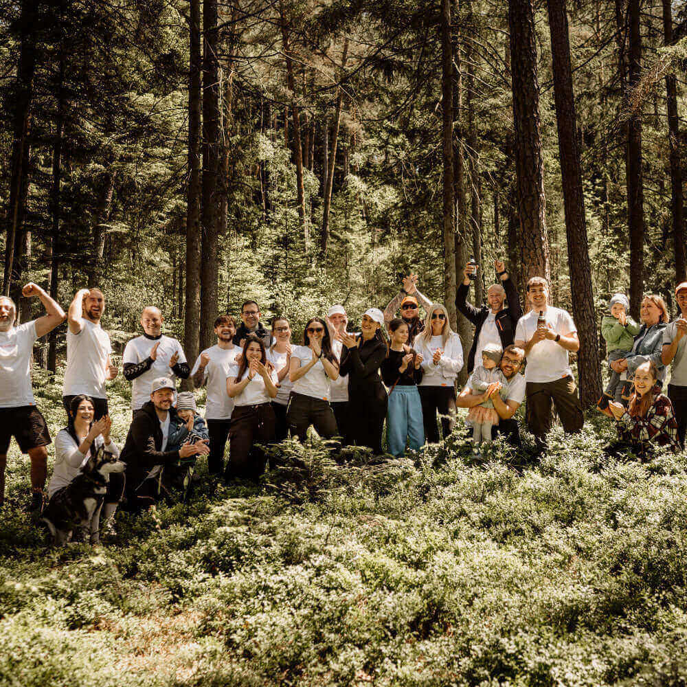 Gruppenausflug in den Wald mit Freunden und Familie, alle in weißen T-Shirts, umgeben von Natur.