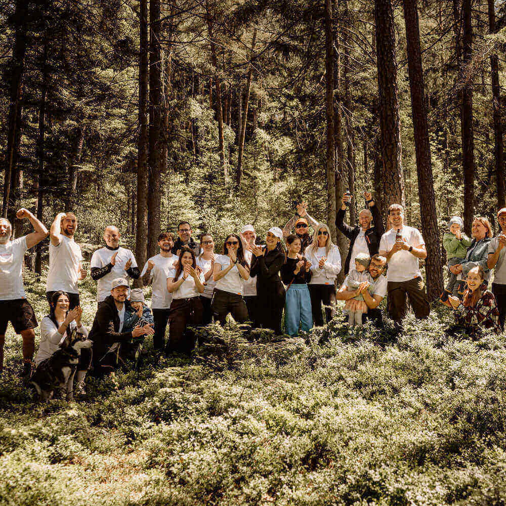 Gruppenausflug in den Wald mit Freunden und Familie, alle in weißen T-Shirts, umgeben von Natur.