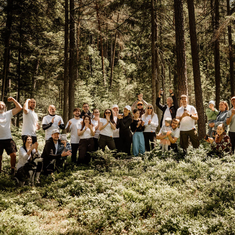 Gruppenausflug in den Wald mit Freunden und Familie, alle in weißen T-Shirts, umgeben von Natur.