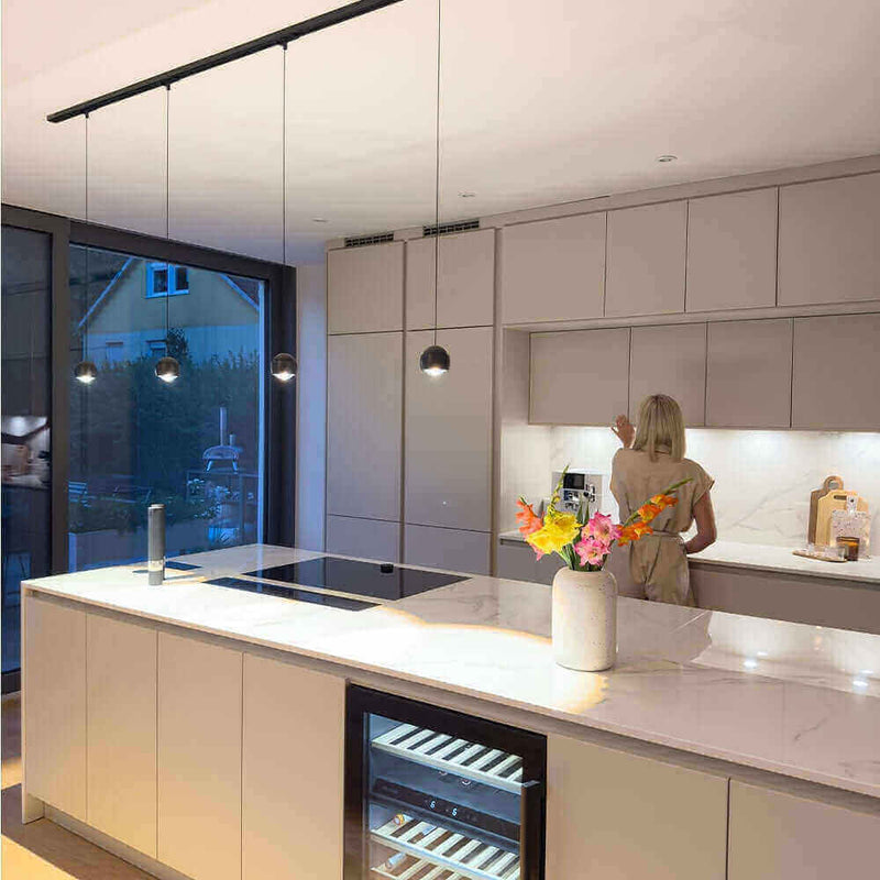 Moderne Küche mit eleganter Beleuchtung und einer Frau, die an der Arbeitsfläche arbeitet.