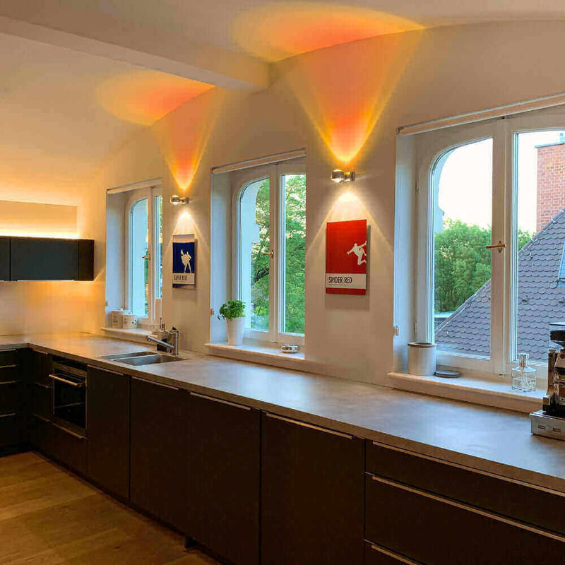 Moderne Küche mit stylishen Wandleuchten und Kunstwerken, die den Raum beleuchten.
