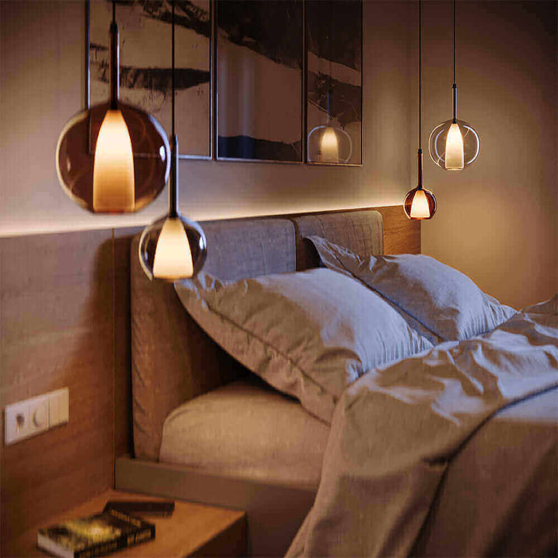 Moderne Schlafzimmerbeleuchtung mit stilvollen Pendelleuchten über einem gemütlichen Bett.