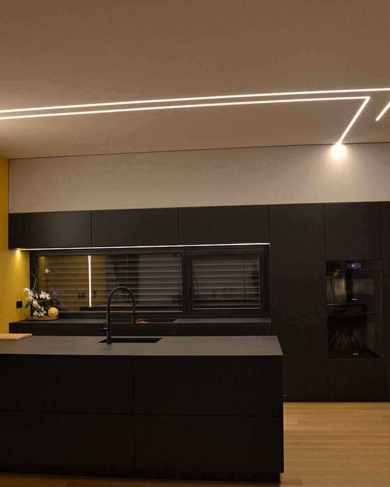 Moderne Küche mit schwarzer Küchenzeile, stilvoller Beleuchtung und Holzfußboden, elegant und funktional.