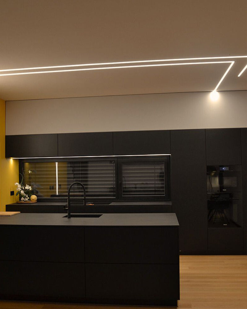 Moderne Küche mit schwarzer Küchenzeile, stilvoller Beleuchtung und Holzfußboden, elegant und funktional.