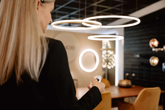 Frau mit Fernbedienung in modernem Raum mit eleganten runden Leuchten und gemütlicher Einrichtung.