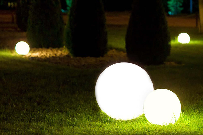 Helle Lichtkugeln im Garten präsentieren eine magische Atmosphäre bei Nacht.