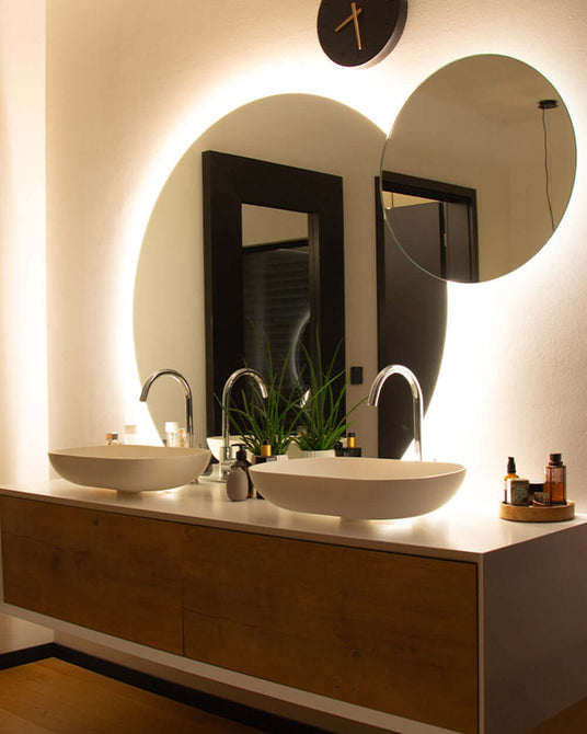 Elegantes Badezimmer mit zwei Waschbecken, großen Spiegeln und moderner Beleuchtung.