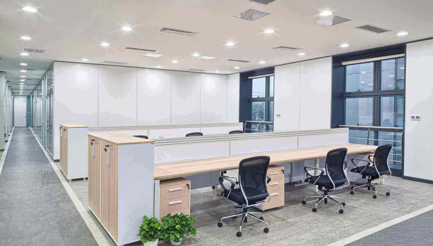 Modernes Büro mit einem offenen Layout, hell erleuchtet, mit Schreibtischen und Bürostühlen.