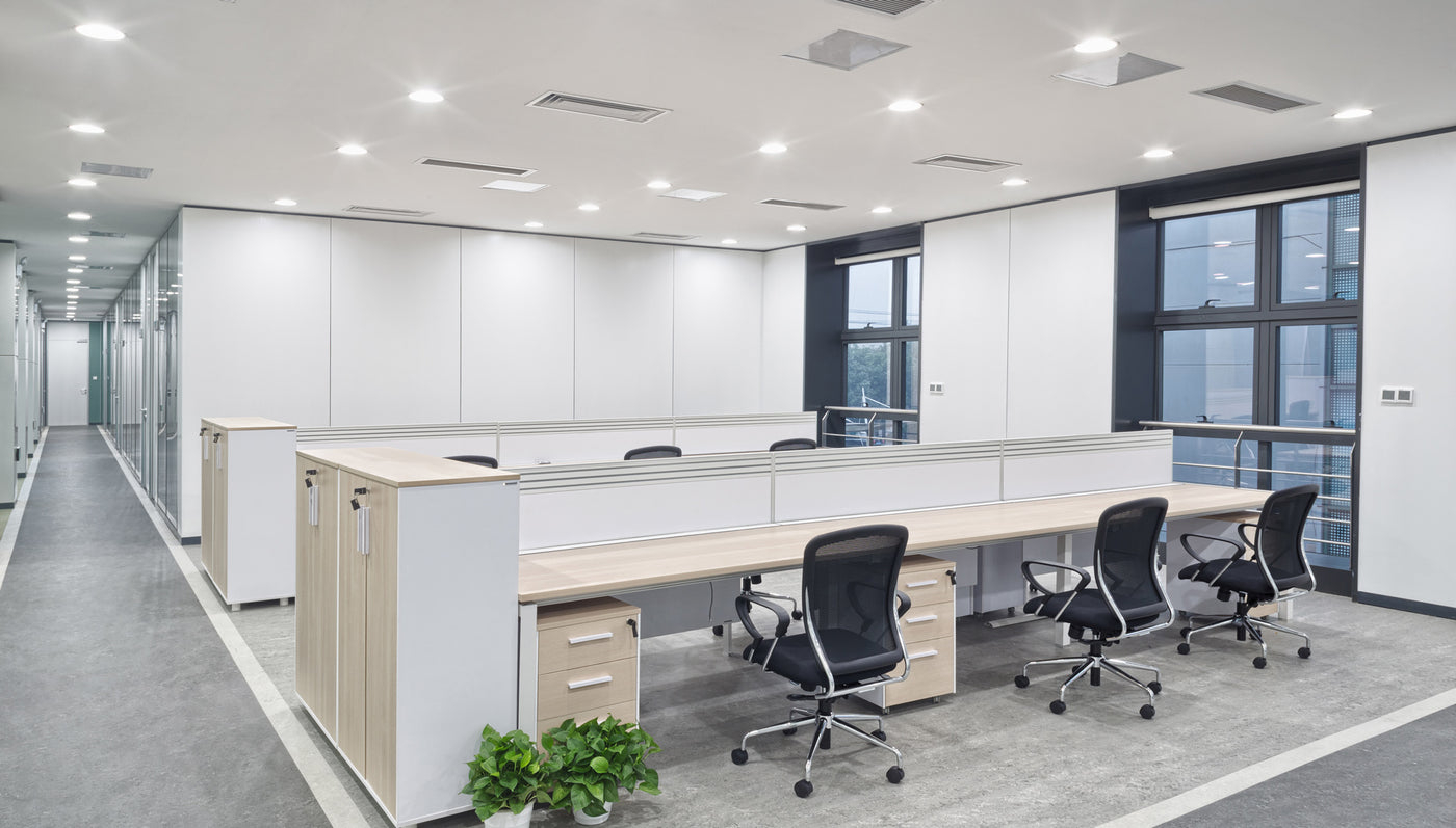Modernes Büro mit einem offenen Layout, hell erleuchtet, mit Schreibtischen und Bürostühlen.