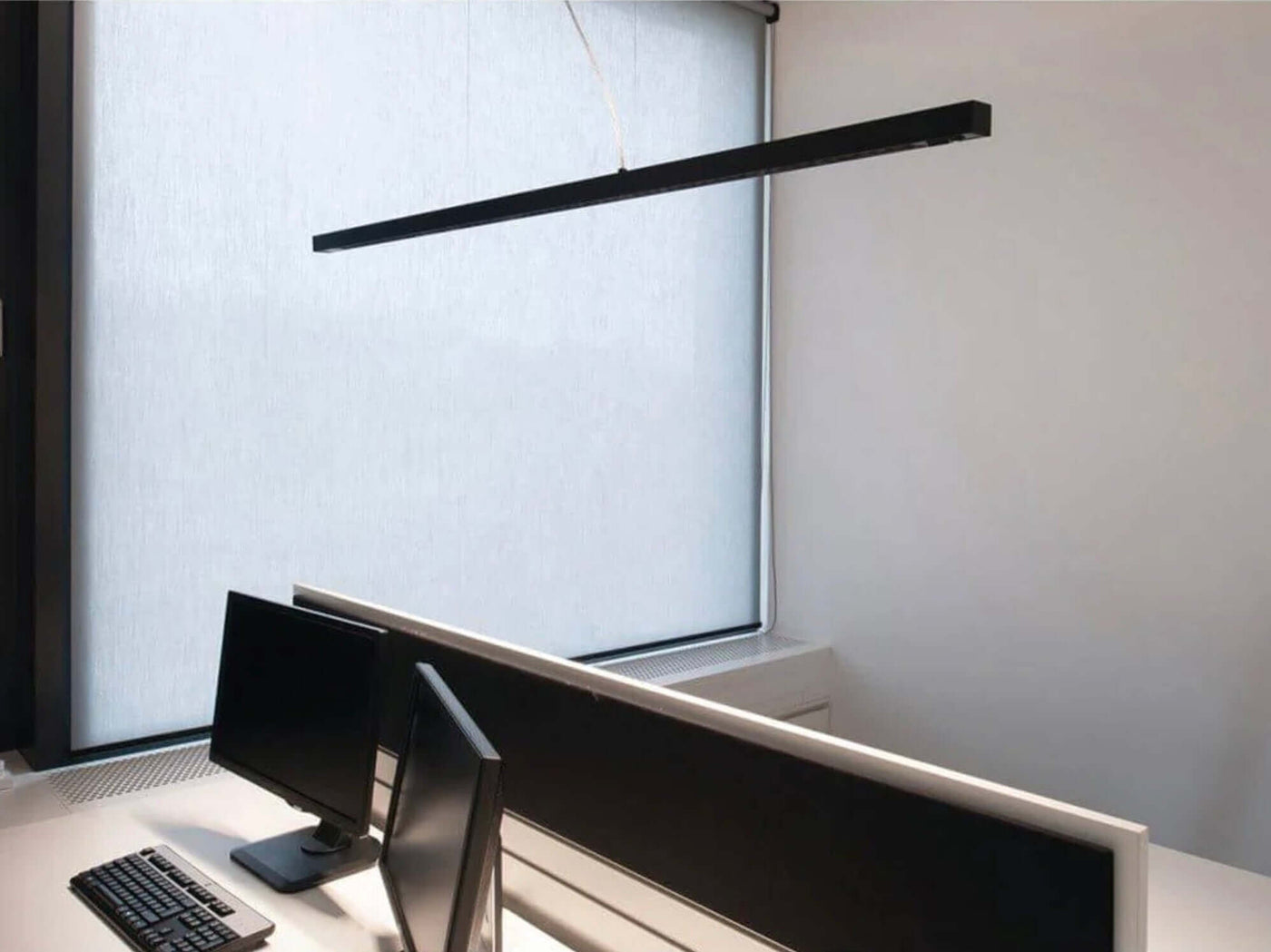Moderne Büroumgebung mit zwei Computermonitoren und einer eleganten Fensterblende, die diffuses Licht bietet.
