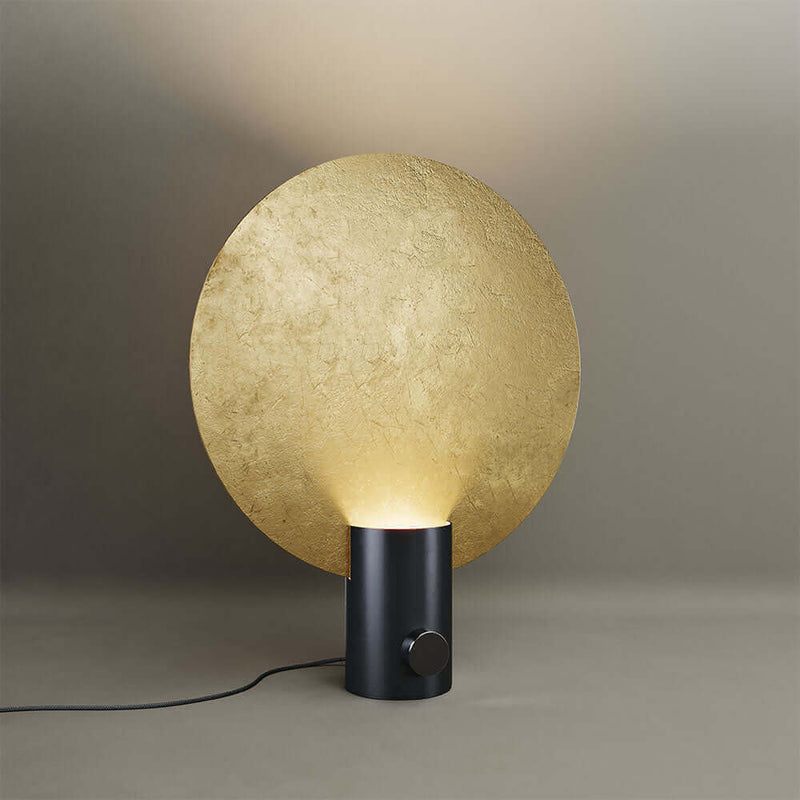 Moderne Lampe mit goldenem Schirm und schwarzem Fuß, stilvoll beleuchtet für elegantes Ambiente.
