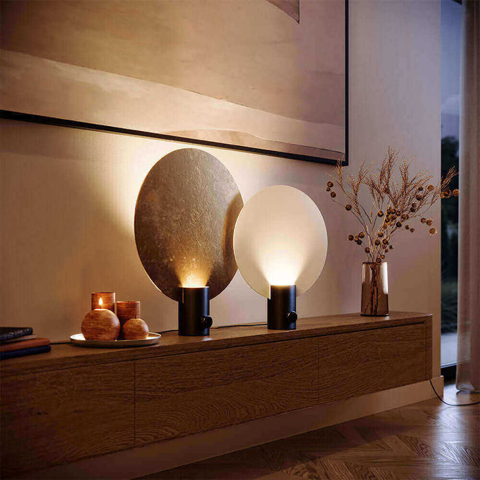 Moderne Tischlampen auf einer Holzkommode, mit warmem Licht und dekorativen Elementen im Hintergrund.