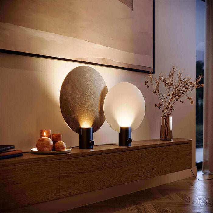 Moderne Tischlampen auf einer Holzkommode, mit warmem Licht und dekorativen Elementen im Hintergrund.